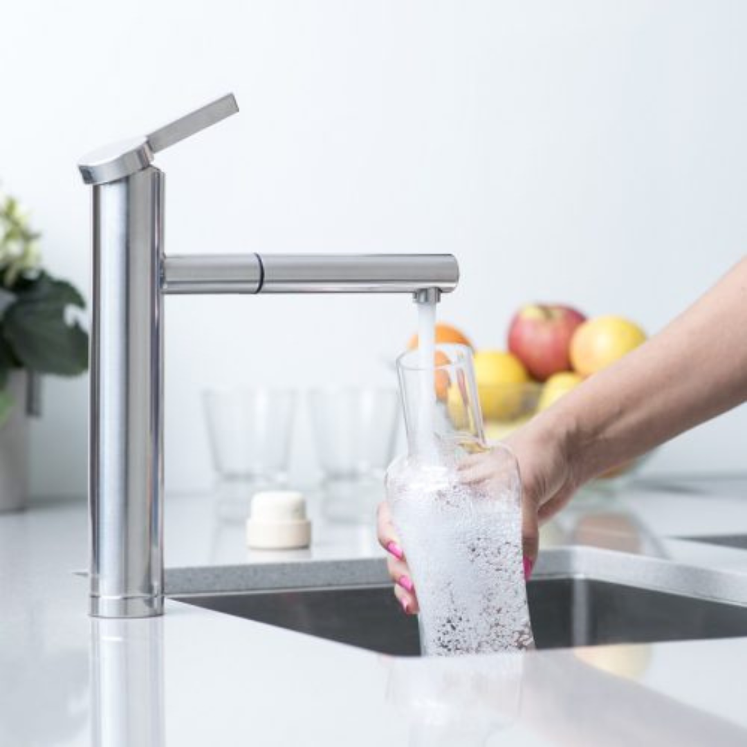 Flaška JUG VODAN glass water carafe being filled at a kitchen faucet